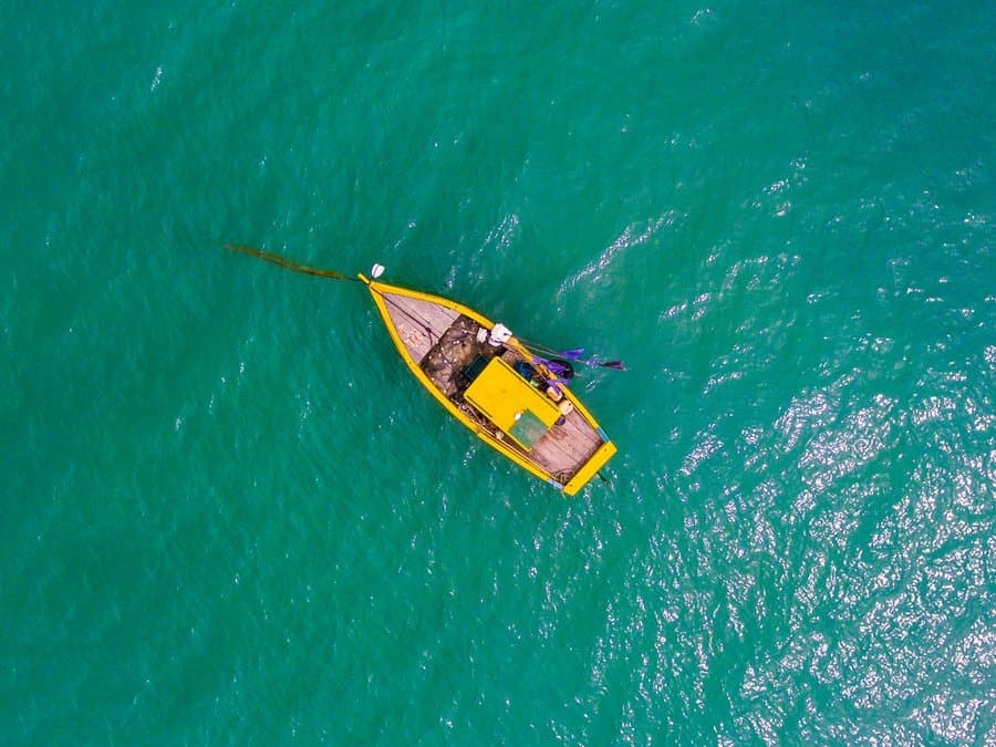 Barco a remo em águas turquesa na Praia do Curuípe, Porto Seguro